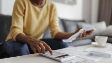 Person using calculator and holding piece of paper